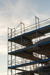 Scaffold in front of a house that is built. Shot during the evening sun of the day. Vertical shot.