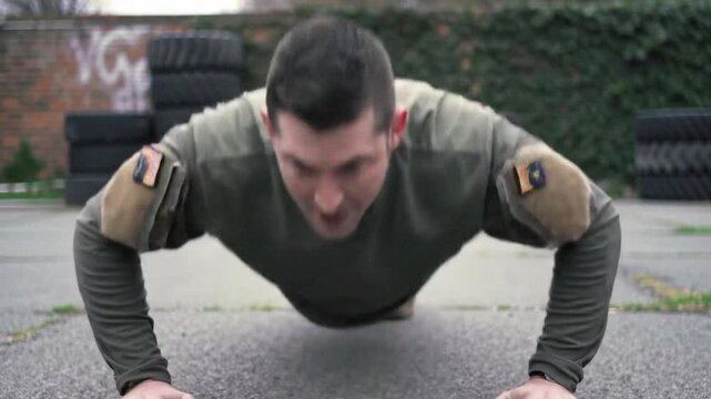 A soldier in uniform performs intense push-ups during an outdoor physical training session