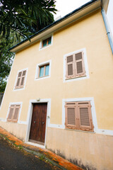 Yellow house with wooden shutters and door on a sloping street
