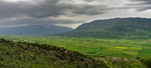 Obraz premium Dramatic Green Valley and Mountains under Stormy Sky Panorama