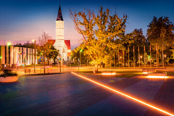 Fototapeta premium Illuminated night view of empty square with St. Peter and Paul cathedral on background. Amazing summer cityscape of Siauliai town, Lithuania, Europe. Traveling concept background.