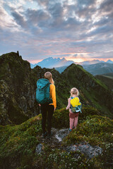 Obraz premium Family mother and daughter travel in Norway - hiking in mountains exploring Lofoten Islands on summer vacations backpacking camping trip, parent and kid climbing together enjoying sunset view