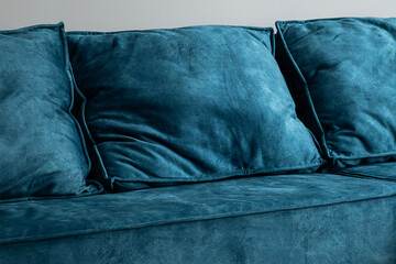 Close up of teal blue sofa cushions made of velvet fabric.