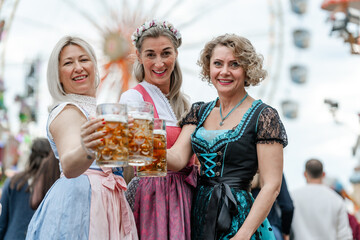 Bavarian women in traditional clothing celebrate with beer mugs at a German festival like Oktoberfest or Maidult