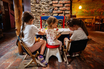Obraz premium Young children engaging in creative activities around a small table in a colorful room