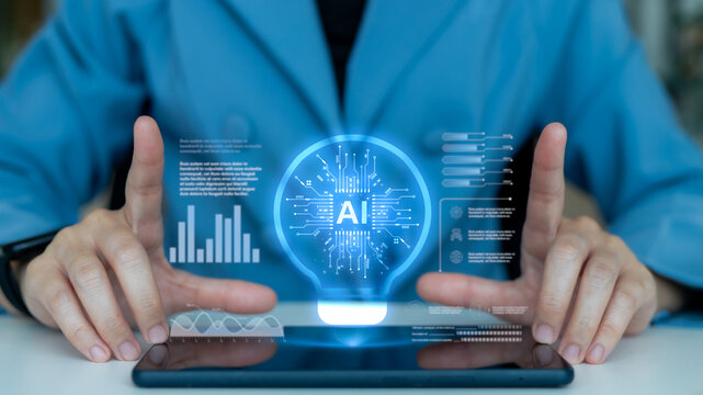 Hands interacting with a digital tablet showing an AI light bulb icon, data graphs, and a futuristic dashboard, representing artificial intelligence and data-driven innovation. - Powered by Adobe