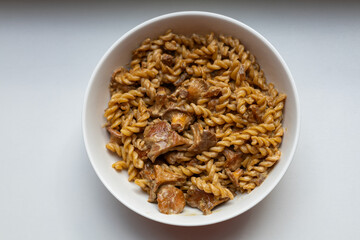 Delicious creamy pasta with chanterelle mushrooms served in a white bowl. Top down food shot for recipe blogs, cooking magazines, or restaurant menus. Rustic comfort food at its best.