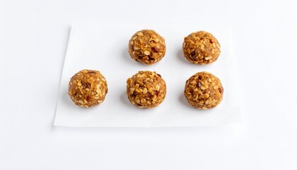 Five homemade oatmeal energy balls arranged on white parchment paper against a white background.