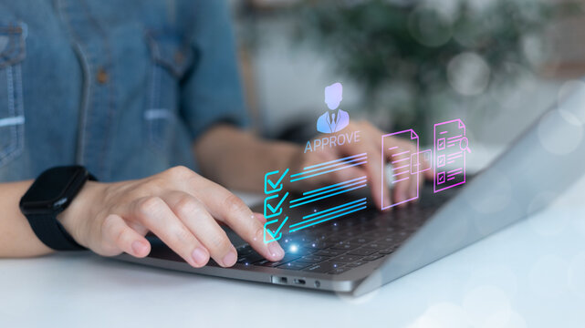 Close-up hand typing on laptop with holographic checklist and approval icons, showing digital verification system, document review process, and remote work approval workflow.