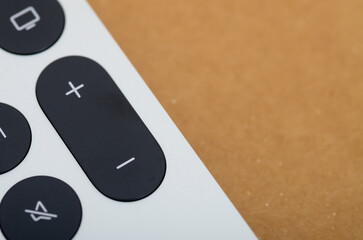 A close-up view of a remote control shows the volume buttons, with a plus (+) for increasing volume and a minus (-) for decreasing it.