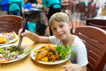 Cute boy, child, eating seafood in a restaurant in Vietnam, tasting traditional vietnamese cuisine