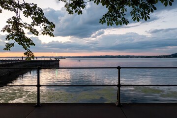 Tranquil lake at sunset with pier and trees.