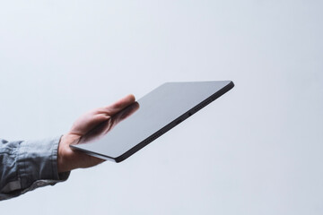 Close-up of male hands holding modern tablet with screen mockup on light background. Concept of business communication services, mobile applications and online education.