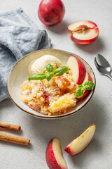 Peach crumble or cobbler with vanilla ice cream scoops and cinnamon on a plate on a light background
