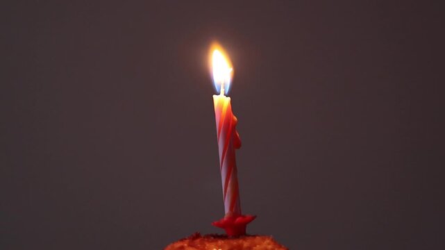 Una toma de cerca de una vela blanca con rojo de cumplea&ntilde;os  con llama colocada en un dulce