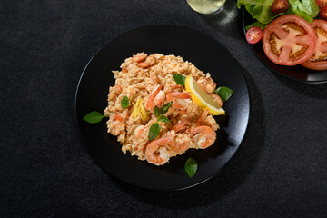 Delicious Shrimp Risotto on a Black Plate, Garnished with Herbs