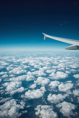 Fototapeta premium Airplane Wing Above Clouds Flying High in Blue Sky