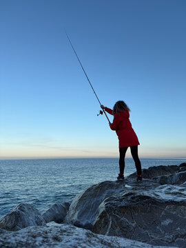 Young happy woman is fishing at sea during spring vacation