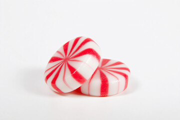 two peppermink candy pieces on a white surface