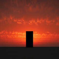 Black monolith standing against a vibrant orange sunset sky with scattered clouds