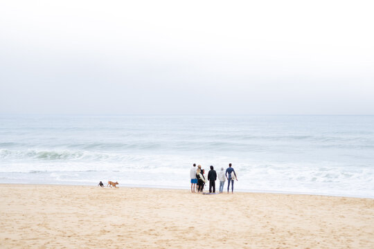 Group of people at beach during surf contest on cloudy day.