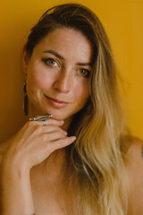 Portrait of a girl with long hair on the background of a yellow wall in costume jewelry