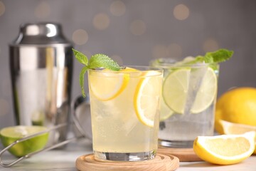 Tasty citrus cocktails in glasses on table against blurred lights, closeup