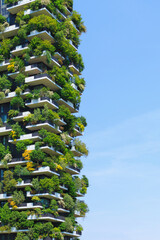 Fototapeta premium A stunning view of a green covered sustaineble building showcases innovative architecture blending nature and urban living under clear sky.