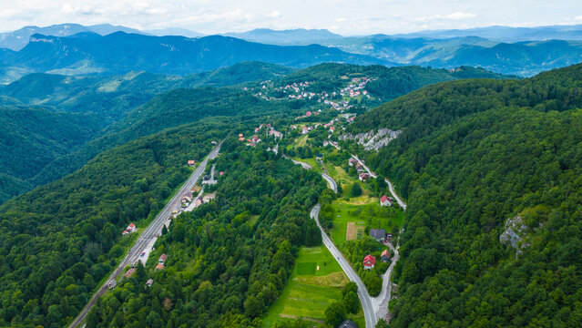 Aerial view of Skrad town and Zeleni Vir area in Gorski Kotar, Croatia. Scenic mountain landscape with green forest, winding roads, and scattered houses in lush nature