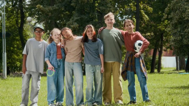 Group portrait of six multiethnic pre-teen friends smiling for camera during outdoor activities in park