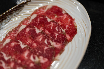 A white plate of raw beef slices ingredient in hot pot restaurant.