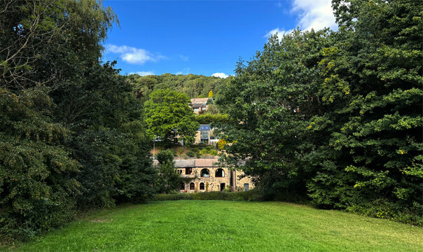 A serene town tucked in woodland, glows under a cobalt sky, its stonework softened by summer light in Holmfirth, Huddersfield, UK
