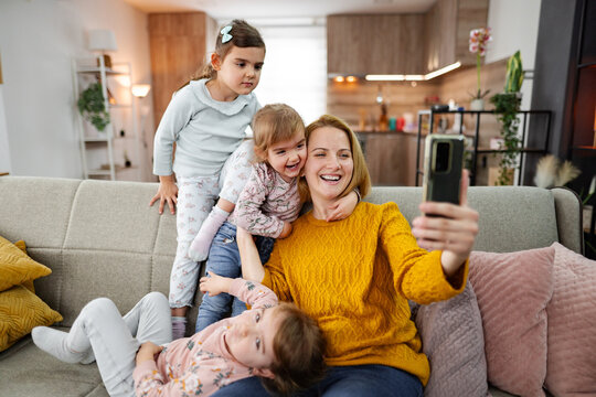 Mother and her three little daughters taking selfies at home