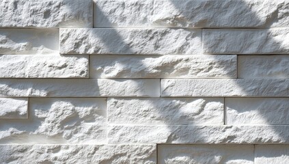 Close-up of a white stone wall with textured bricks, sunlit and casting shadows