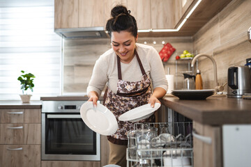 Woman loading the dishwasher in the kitchen