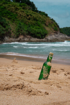 Green Bottle Glass Of Water On The Beach