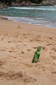 Green Bottle Glass Of Water On The Beach