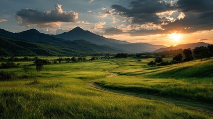 Scenic valley at sunset. Lush green fields, winding path, mountains, dramatic sky