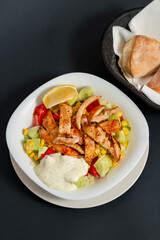 Caesar salad with chicken in a white plate. Dark background. Close up. Top view. Healthy food, keto diet, diet lunch concept.