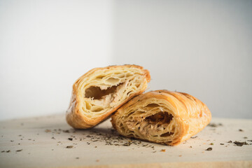 A close-up view of puff pastries sliced in half, showing their flaky layers and savory filling. Sprinkled aromatic herbs enhance the presentation, offering a rustic and appetizing scene.