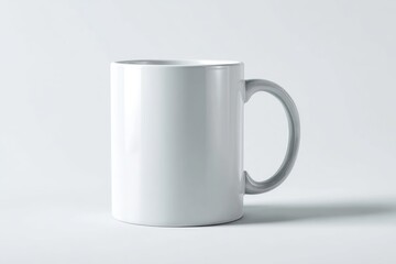 Fototapeta premium A plain white ceramic mug with a C-shaped handle sits on a light grey background, casting a subtle shadow