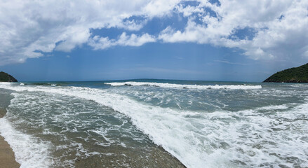 Beautiful panoramic view of beach landscape and foam under a blue sky full of clouds 