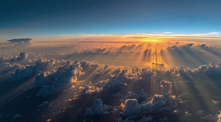 Aerial view of a sunset over a vast cloud field. Sunbeams pierce through the clouds, illuminating the scene.  A panoramic vista of the atmosphere