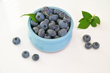 Blueberries in a blue cup on a white isolated background.