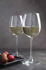 Tasty wine in glasses and truffle bonbons on grey table, closeup