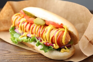 Tasty hot dog with vegetables, mustard and ketchup on wooden table, closeup