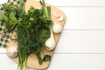 Different fresh herbs, green onions and garlic on white wooden table, flat lay. Space for text