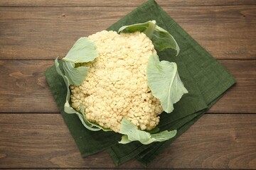 Fresh cauliflower with green leaves on wooden table, top view