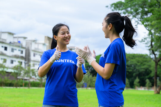 Volunteers showing thumbs up and wearing gloves in a park