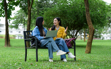 Two students studying together with laptop and books in park